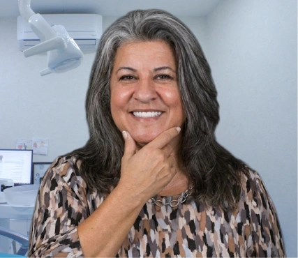 Confident Latina woman with grey hair pointing to her natural-looking smile