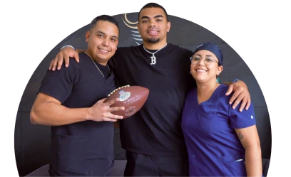 Satisfied professional football player patient posing with expert dental staff at a modern dental clinic