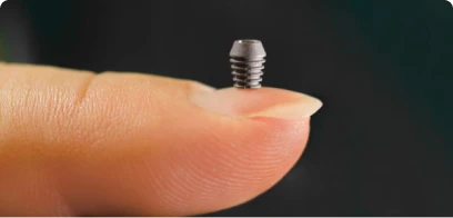 A tiny Bicon SHORT dental implant resting on a fingertip to demonstrate its compact size