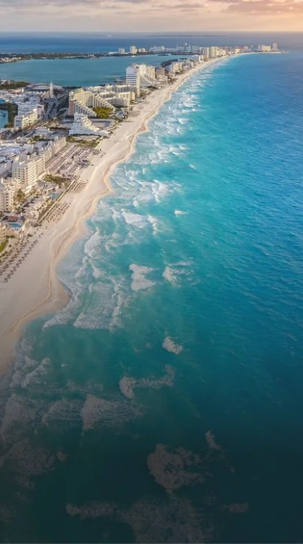 Aerial view of the Cancun Hotel Zone coastline, featuring white sand beaches, resorts, and the turquoise Caribbean Sea.